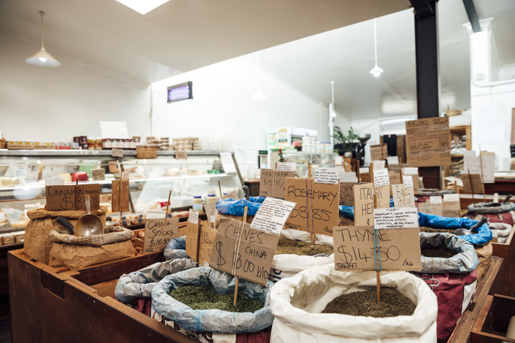 Wide shot of an empty supermarket in Australia. There are sacks of herbs and spices in the foreground.