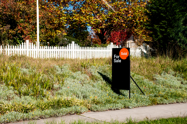 For sale sign near the residential building house with 'SOLD' sold sticker on it. Auction clearance rate