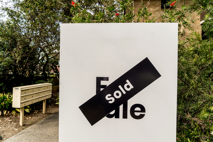 White for sale sign near the resedential appartment building with sold sticker on it. Real estate property investment boom White for sale sign near the resedential appartment building with sold sticker on it. Real estate property investment boom
