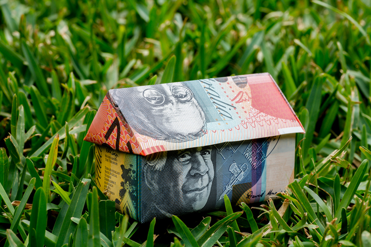 Origami house made with Australian Note money sitting on grass lawn